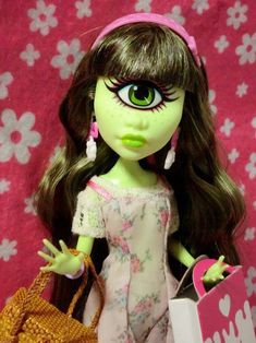 a doll with green eyes and long hair holding a handbag in front of a pink background