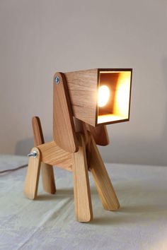 a wooden table lamp with a small light on it's head and legs in the shape of a dog