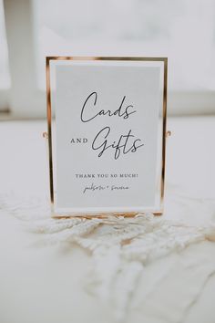 a card and gifts sign sitting on top of a white tablecloth covered floor next to a window