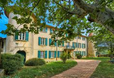 an old house with green shutters and trees