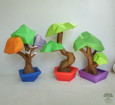 three paper trees sitting in small colorful pots