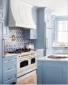 a blue and white kitchen with an oven, range, counter tops and cabinets in it