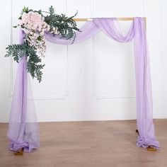 a purple wedding arch decorated with flowers and greenery