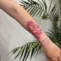 a woman's arm with a red dragon tattoo on the left side of her arm