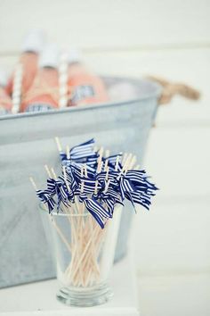 toothpicks are placed in a glass vase on a white tablecloth with blue and white striped straws