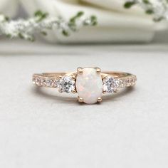 This beautiful ring is made from 14K Solid Rose Gold with Rhodium plating. Ring details- -The Main stone is an oval cut 7mm by 5mm Lab Created White Fire Opal Stone -Side stones are round 3mm and 1.5 clear simulated diamonds -Ring is casted in 14K Solid Rose Gold with Rhodium plating ( 14K Solid Yellow Gold and 14K White Gold also available, please check the drop down menu for more options) -The Total face height of the ring measures 7mms and the band width measures 2mms -Each ring is handmade a Rose Gold Ring With Round Stone For Anniversary, Rose Gold Round Cut Cluster Ring In Fine Jewelry, Rose Gold Round Halo Promise Ring, Rose Gold Round Halo Ring For Promises, Rose Gold Round Cut Cluster Ring, Formal Rose Gold Opal Ring, White 14k Rose Gold Ring For Gift, 14k Rose Gold White Rings As Gift, 14k Rose Gold White Rings Fine Jewelry