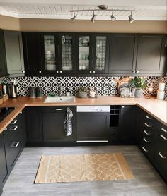 a kitchen with black cabinets and white tile backsplashes, an area rug on the floor