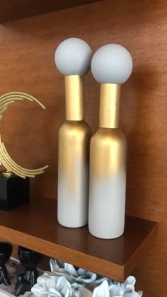 two white and gold vases sitting on top of a shelf next to other items