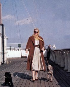 a woman is walking her dog on the deck of a ship while another dog watches