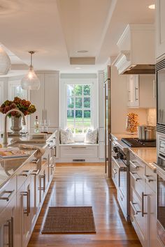 a large kitchen with white cabinets and wood flooring, along with a window seat