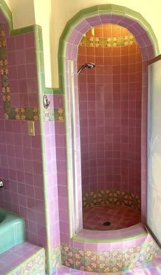 a bathroom with pink tiled walls and purple tile flooring, shower stall and sink