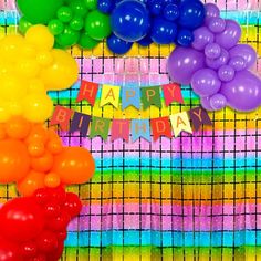 there are many balloons and streamers on the table with happy birthday sign in front of them