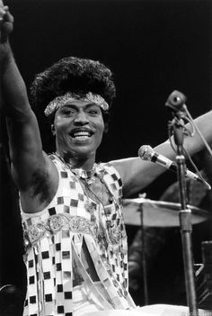 a black and white photo of a woman with her arms in the air as she sings into a microphone