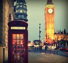 a red phone booth sitting next to a tall clock tower