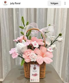 a basket filled with pink and white flowers on top of a table next to a card