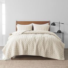 a bed with white quilts and pillows in a room