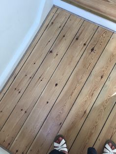 a person standing on top of a wooden floor next to a white wall and stairs