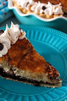 a piece of pie on a blue plate with whipped cream and chocolate chips around it