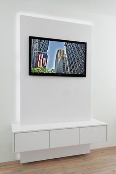 the television is mounted on the wall in the room with wood flooring and white walls