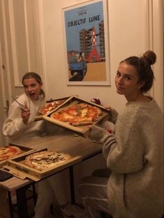 two women sitting at a table eating pizza