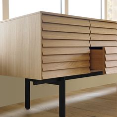 a wooden cabinet sitting on top of a hard wood floor in front of a window