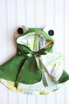 a green frog hat and bib on a white wall