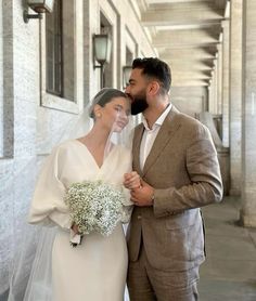 a bride and groom standing in front of a building