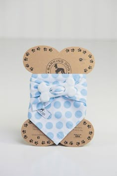 a blue and white polka dot dog bandana on top of a cardboard package with paw prints