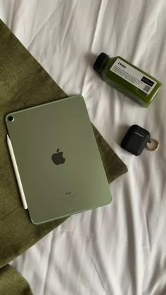 an apple ipad sitting on top of a bed next to a bottle of green tea