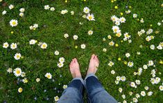 someone standing in the middle of a field with daisies on it's ground