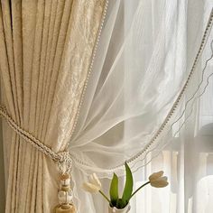 a vase with flowers in it sitting on a window sill next to a curtain