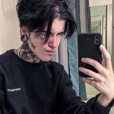 a man with black hair and piercings taking a selfie in front of a mirror