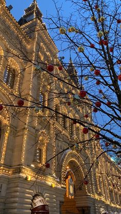 a large building with christmas lights on it's side and a tree in the foreground