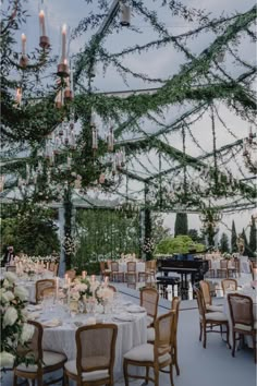 an outdoor dining area with chandeliers and tables set for formal function at dusk