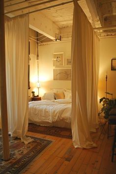 a bedroom with four poster bed and white drapes hanging from the ceiling above it