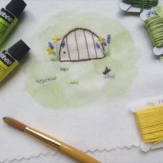 some crafting supplies are laying out on a white tablecloth with green and yellow thread