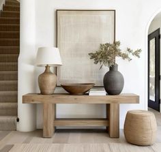 a table with two vases and a lamp on top of it next to a staircase