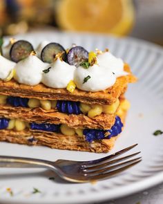 a white plate topped with layered dessert next to a fork