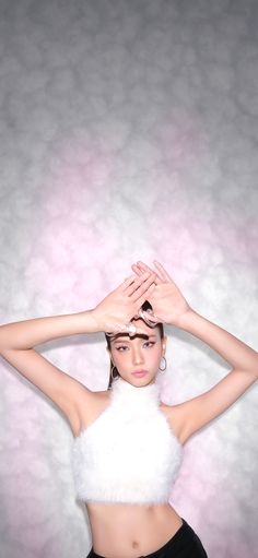 a woman with her hands on her head wearing a white top and black shorts, posing for the camera