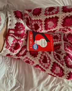 a crocheted blanket on top of a bed next to a stuffed animal and book