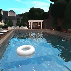 a pool with an inflatable ring floating on it's side next to lounge chairs and trees