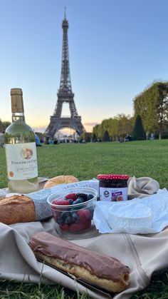 the picnic is set out in front of the eiffel tower, with fruit and bread