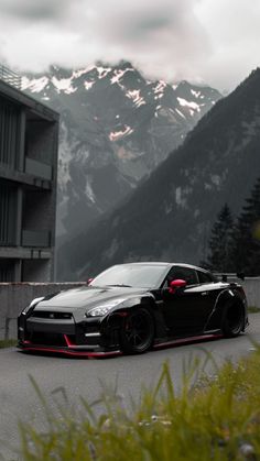 a black sports car parked in front of a building with mountains in the back ground