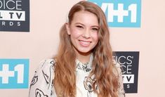 a woman with long hair smiling at the camera