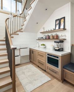 a kitchen with wooden cabinets and stairs in the corner, along with a white rug on the floor