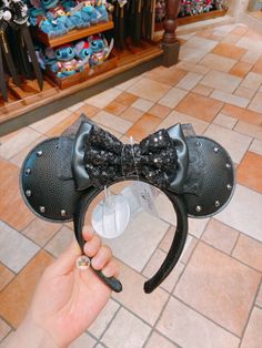 a person holding up a mickey mouse ears headband in front of a store display