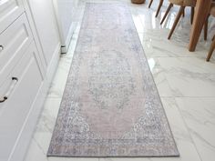 a large rug is on the floor in a room with white cabinets and wooden chairs