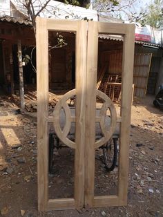 an open wooden door sitting on top of a dirt ground