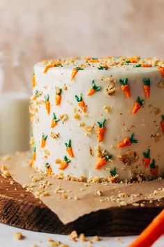 a carrot cake with white frosting and sprinkles on a cutting board