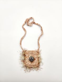 a small purse with a button hanging from it's side on a string necklace